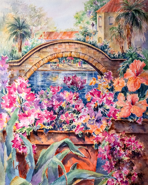 Vivid pink flowers and tropical leaves frame an arched bridge on the San Antonio River Walk.