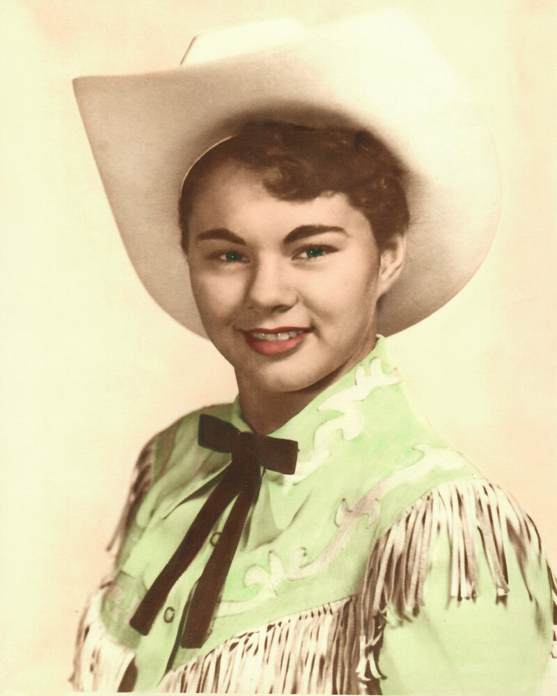 Hand tinted studio portrait of young Donna smiling in a white cowboy hat, mint green fringed western shirt and dark ribbon bow tie.