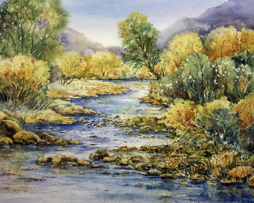 A clear river winds between green and gold trees toward low Texas hills.
